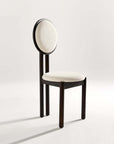 A modern dining chair with a solid ash wood frame and a round upholstered backrest in a neutral color.