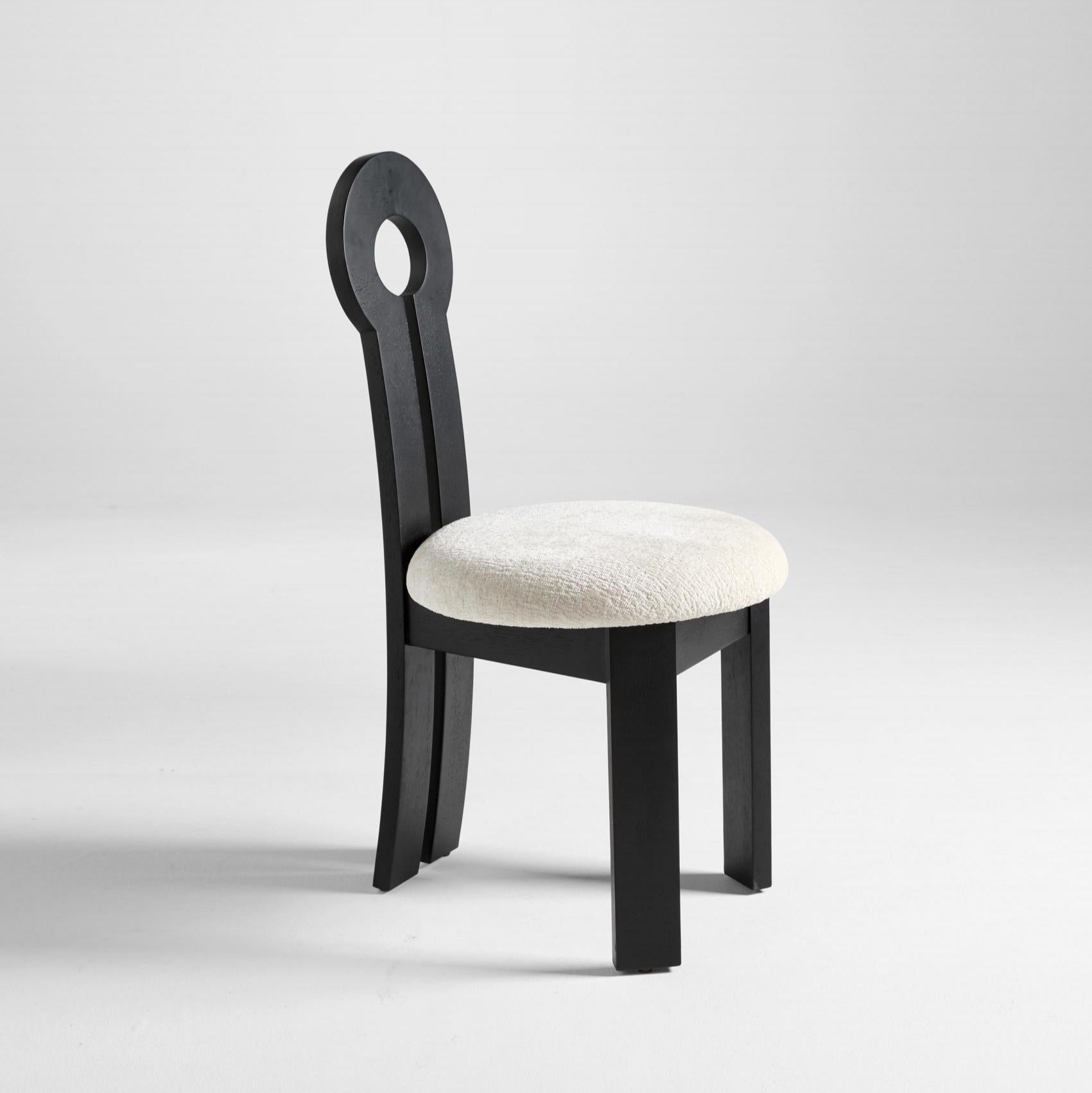 A dining chair with a solid rubber wood frame and a round white upholstered seat, featuring a unique circular design at the top of the backrest.