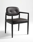 A dining chair with a solid ash wood frame and faux leather upholstery, featuring a buttoned backrest and seat cushion.