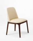 A modern dining chair with a solid ash wood frame in a beige color and faux leather upholstery.